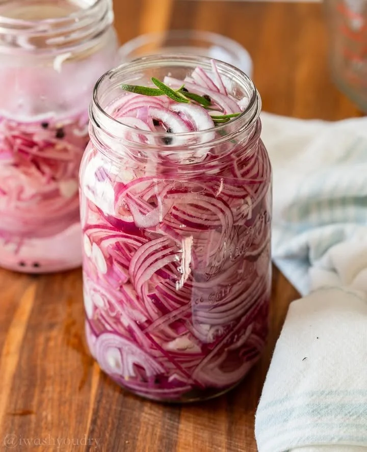 Jar of quick pickled red onions on a rustic table