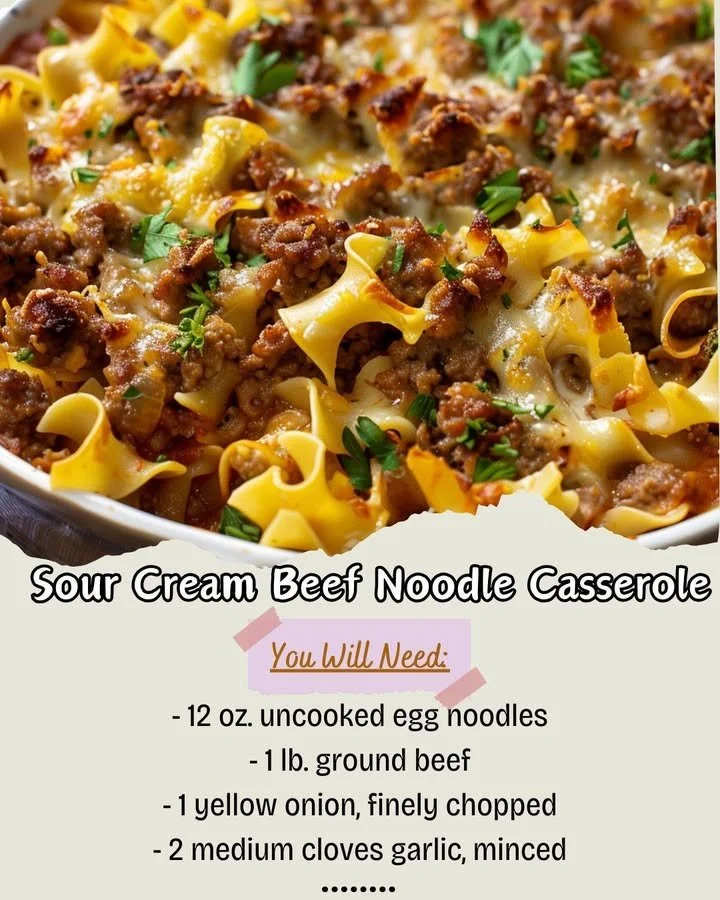 Sour cream beef noodle casserole topped with cheese and herbs in a baking dish.