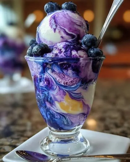 Blueberry and vanilla swirl ice cream parfait in a stylish glass with fresh berries