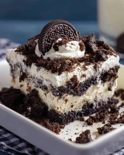 Delicious Oreo Poke Cake topped with cream and Oreo crumbles