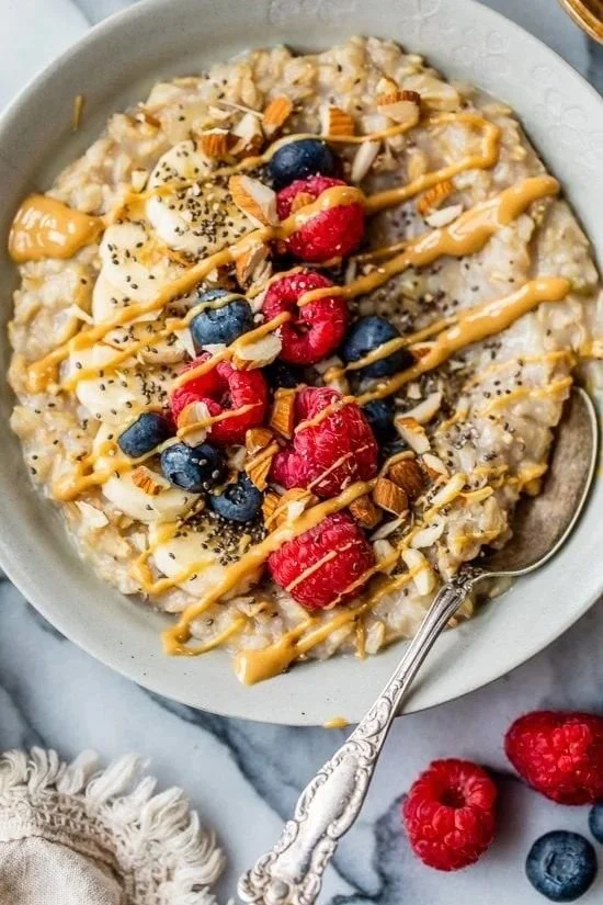 Peanut butter breakfast oatmeal bowl topped with fruits and nuts